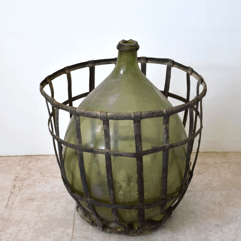 Damajuana antigua de vidrio verde con cesta de hierro