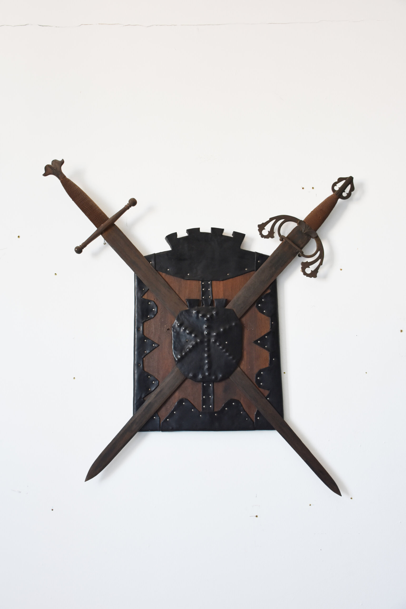 Panoplia decorativa medieval con escudo y dos espadas
